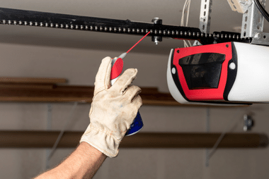 A photo of a hand doing routine maintenance on a garage door