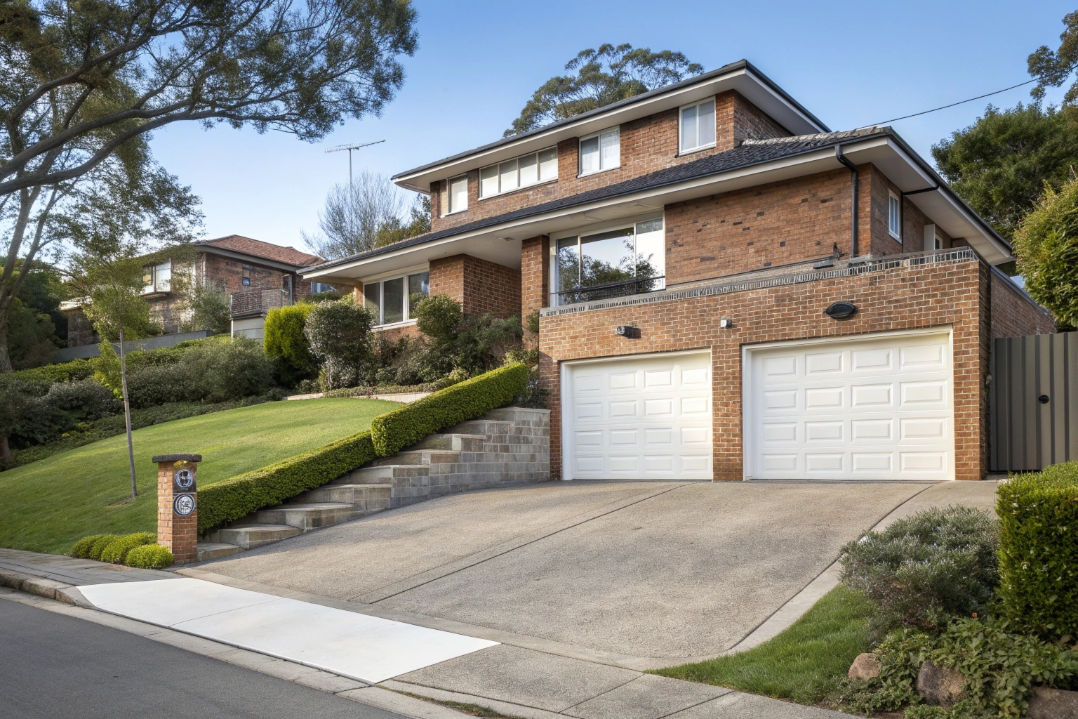 White sectional garage doors on sloped driveway in Artarmon showing elevation installation